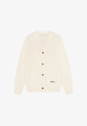 Tejdzsorgó kardigán V nyakkal, öt barna gombbal, két elülső zsebbel, és fekete hímzett szöveggel "les deux" a bal zseben.