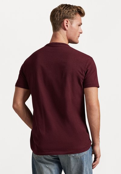 Κοντομάνικο μπλουζάκι μπαρντό από βαμβάκι, με κλασικό ντεκολτέ και λεία υφή, εμφανίζεται από πίσω. Άνετη γραμμή.