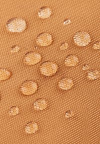 Tkanina odporna na wodę w ciepłym brązowym odcieniu, z wieloma kroplami na teksturowanej powierzchni, podkreślająca jej właściwości ochronne.