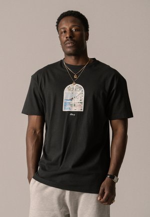 Camiseta de algodón negra con un gráfico frontal de una escena de ventana con árboles y agua. Corte casual, con cuello redondo y mangas cortas.