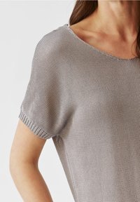 Top grigio a maniche corte con vestibilità ampia. Tessuto lavorato a maglia e scollatura larga, con dettagli a coste sottili su maniche e orlo.
