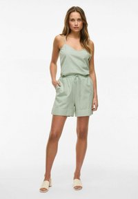 Top sin mangas de color verde claro con tirantes finos y escote en V, acompañado de pantalones cortos a juego con cintura elástica y cordón.