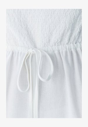 Valkoinen mekko, jossa on teksturoitu yläosa ja sileä, laskostettu hame. Mukana on kiristettävä nyöritys vyötäröllä säädettävää istuvuutta varten.