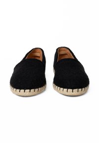 Czarne filcowe buty wsuwane o zaokrąglonym kształcie, z podeszwami z juty i kontrastowym przeszyciem wzdłuż obwodu. Miękka tekstura, bez metalowych elementów.