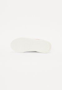 Semelle de basket blanche avec une surface en caoutchouc texturée, présentant un motif de semelle simple et un petit logo de marque en orange sur le côté.