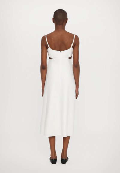 Vestido midi blanco con tirantes finos, cortes abiertos en la espalda y cintura ajustada. Tejido suave con un ligero brillo, que cae por debajo de la pantorrilla.