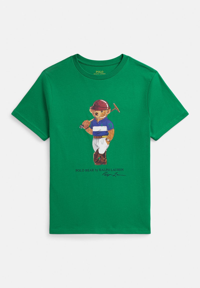 T-shirt verde de algodão com um urso usando um capacete vermelho e uma camisa às riscas azul e branca, segurando um taco de pólo, com a assinatura abaixo.