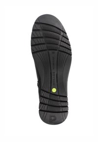 Suela de zapato de goma negra con ranuras profundas para tracción, con un punto de acento verde y marca en relieve en el lateral. Talla 39 indicada.