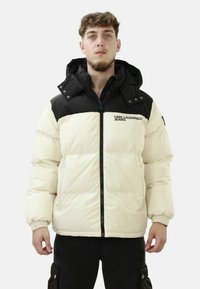 Giacca puffer con un design a blocchi di colore nero e crema, dotata di chiusura con zip, cappuccio e polsini a coste, realizzata in materiale trapuntato e liscio.