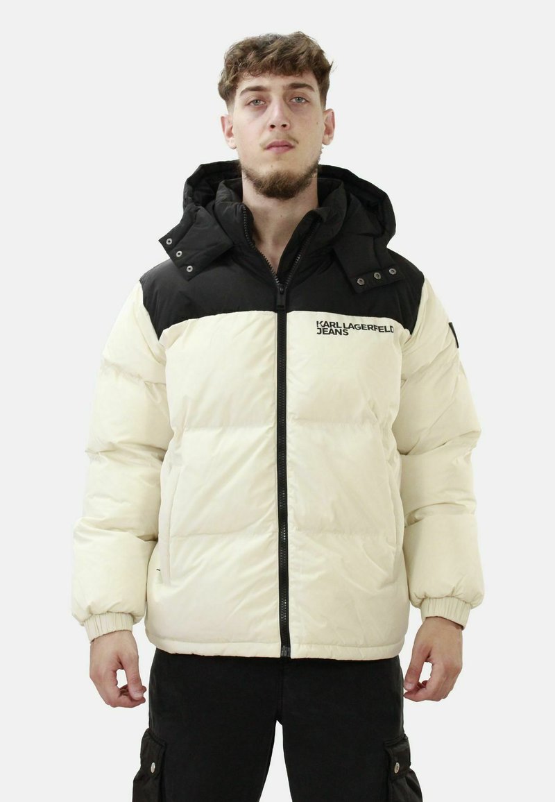 Giacca puffer con un design a blocchi di colore nero e crema, dotata di chiusura con zip, cappuccio e polsini a coste, realizzata in materiale trapuntato e liscio.
