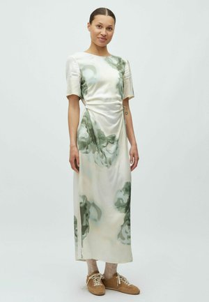 Długa, jedwabna sukienka w zielone kwiatowe wzory na kremowym tle, z krótkimi rękawami i marszczeniem w talii. Do tego dobrane teksturowane buty.