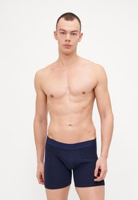 Námornícke modré boxerky vyrobené z mäkkého, elastického materiálu s elastickým pásom, na ktorom je logo značky. Úzky strih s krátkym nohavicami.
