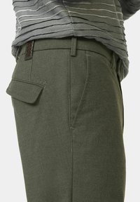 Groene wolmix broek met een getailleerde pasvorm en zijzakken. Heeft een achterzak en een gestructureerd leren accent boven de tailleband.