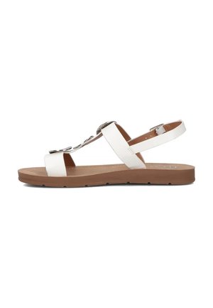 Białe sandały z płaską brązową podeszwą, z designem na T, regulowanym paskiem wokół kostki oraz metalowymi akcentami. Gładka tekstura.