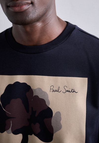 Schwarzer Kapuzenpullover mit einem großen abstrakten Blumendesign in dunklem Burgunderrot und Grau, mit der Signatur "Paul Smith" darunter aufgedruckt.