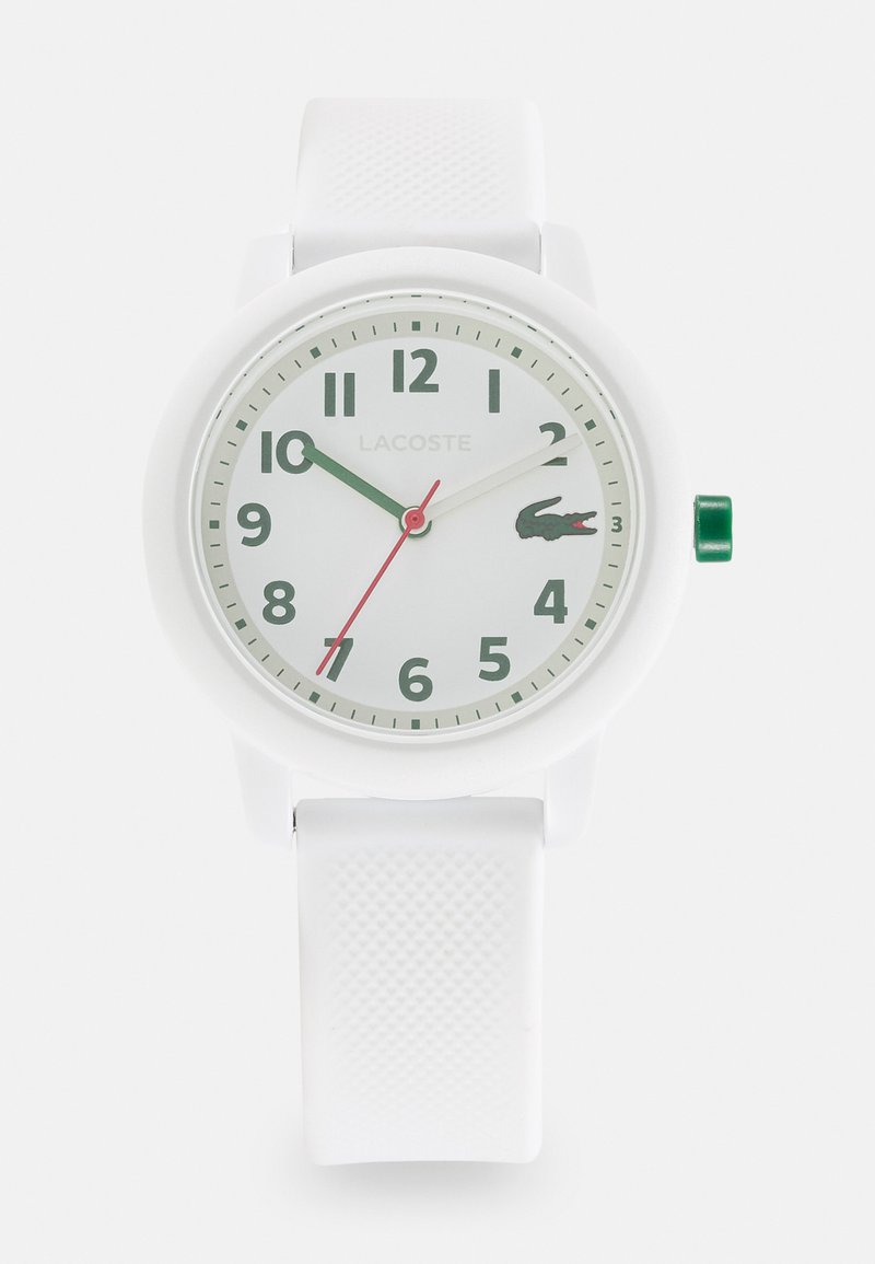 Ceas alb din silicon cu carcasă rotundă, marcaje ore verzi, secundar roșu și logo-ul Lacoste. Curea texturată pentru aderență. Cataramă ajustabilă.