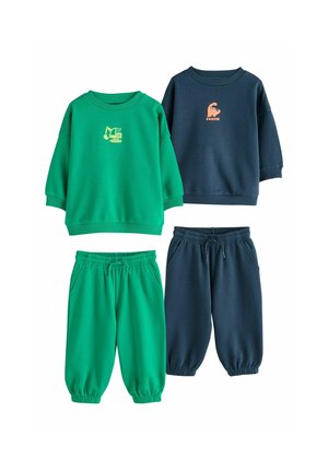 Ung blond dreng iført en marineblå sweatshirt med et orange dinosaurmotiv og ordet "ROARRR" trykt på.