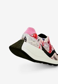 Sneaker con colletto in suede rosa, suola intermedia bianca, suola esterna nera e una stampa colorata con motivi di giornali e design astratti.