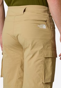 Pantaloni cargo beige realizzati in materiale leggero, con tasche laterali e logo The North Face bianco sul retro.