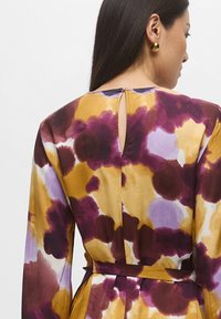 Abito a maniche lunghe con un motivo floreale multicolore in viola, giallo e crema. Presenta un'apertura a chiave sul retro e un dettaglio in tessuto a cintura.