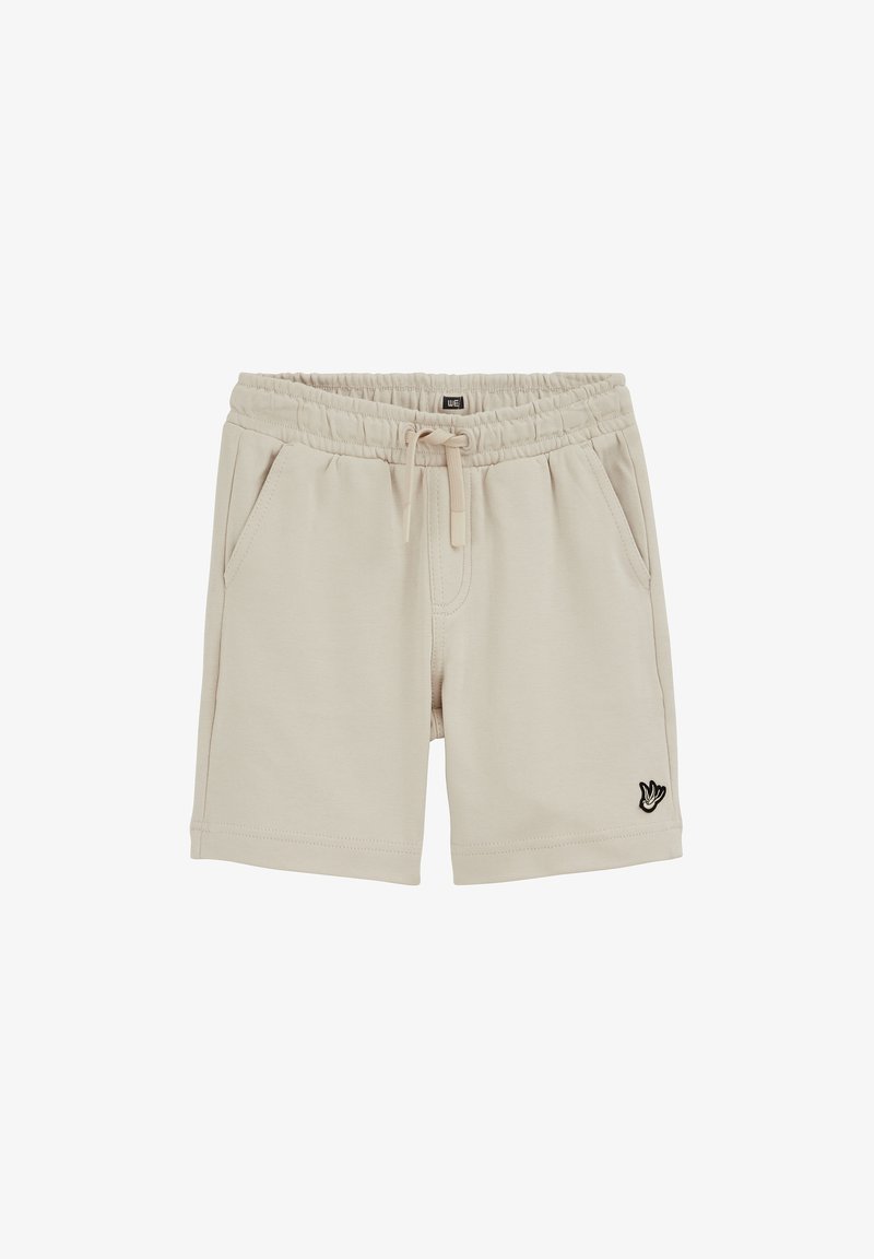 Short beige avec taille élastique, cordon de serrage, poches latérales et petit logo oiseau noir et blanc sur la jambe gauche.