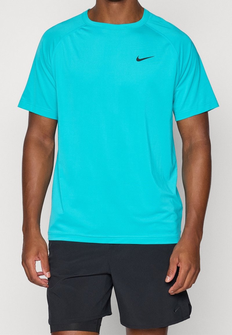 Homme portant un t-shirt de sport turquoise vif à manches courtes avec le logo Nike noir et un short de sport noir avec un petit logo Nike.