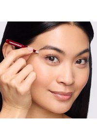 Pinces à épiler Tweezerman rouges tenues par une personne, dotées d'une pointe inclinée pour un façonnage précis des sourcils, avec une finition lisse et brillante et un logo bien visible.