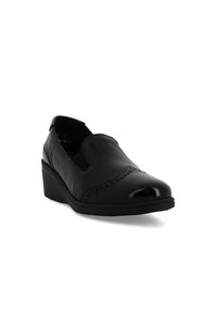 Scarpa nera in pelle senza lacci con tacco a piccolo wedge, dettagli brogue sulla punta e pannelli elastici laterali per una facile calzata.