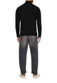 Czarna koszula z długim rękawem i wysokim kołnierzem, w zestawie z szarymi, luźnymi dżinsami i białymi sneakersami. Posiada subtelne detale w tylnej kieszeni.