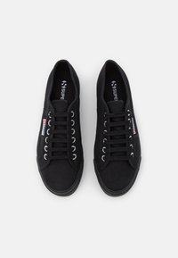 Svarta kanvas sneakers med en texturerad ovandel, åtta metallöglor för snörning och en gummisula med en logotagg på sidan.