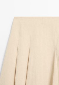 Høj talje beige nederdel med lodrette syede læg og glat stoftekstur.