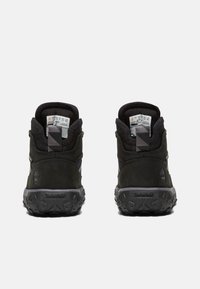 Zwarte enkellaarzen van een combinatie van suede en synthetische materialen. Stevige rubberen zolen, gevoerd kraagje en reflecterende accenten.