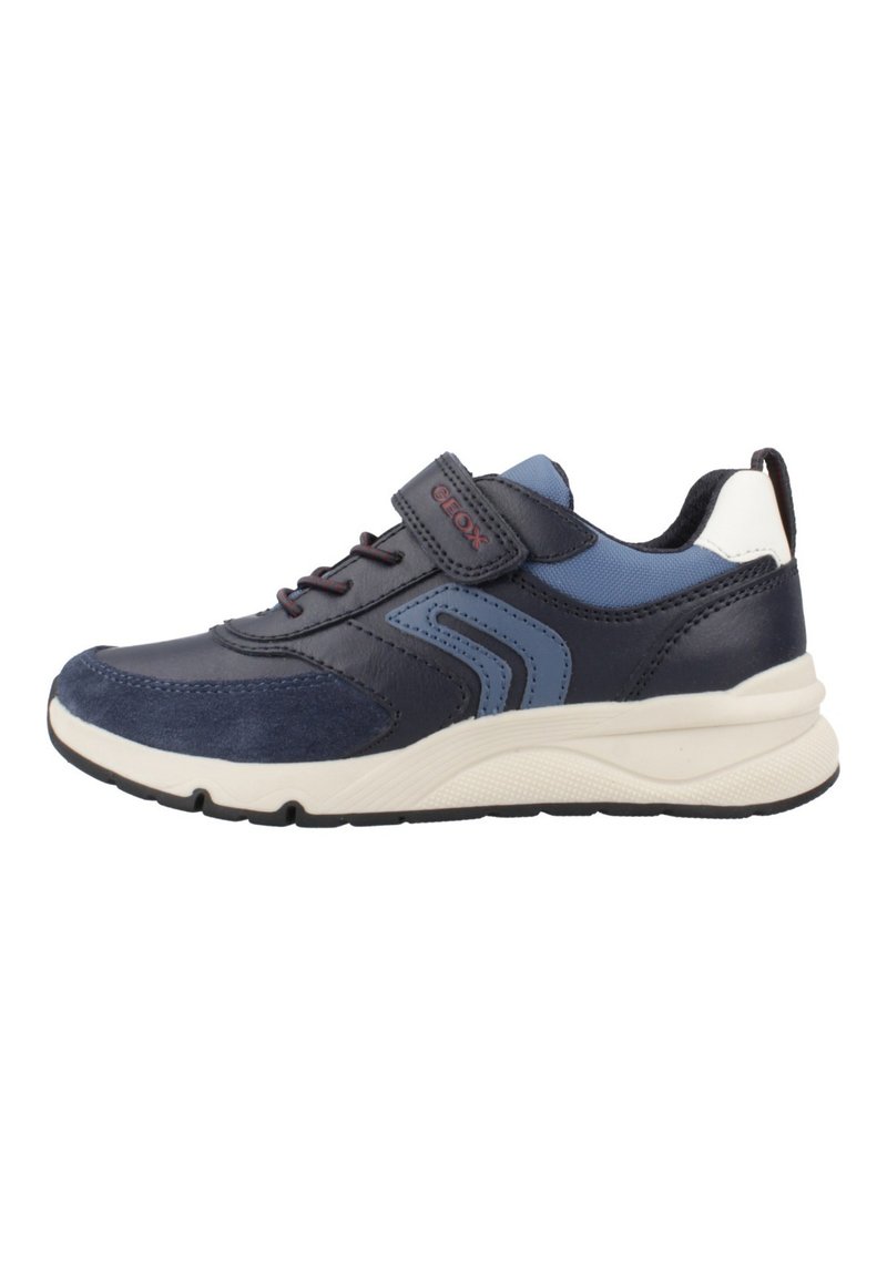 Chaussure de sport bleu marine avec une tige en cuir et en daim, bande Velcro, semelle rembourrée et accents texturés. Présente un design respirant.