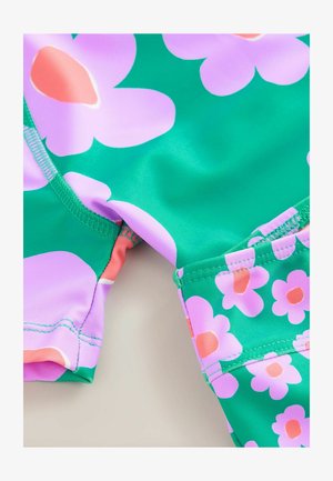 Zielona odzież kąpielowa z dużymi różowymi kwiatami i brzoskwiniowymi środkami. Gładki, elastyczny materiał z kontrastowymi różowymi detalami i wykończeniami szwów.