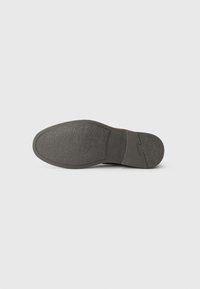 Black rubber shoe sole with textured surface, rounded toe, and slight heel. Features a smooth edge and subtle branding.