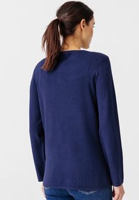 Maglione a maniche lunghe blu navy con scollo rotondo, tessuto liscio e vestibilità rilassata. Design semplice senza motivi o dettagli visibili.