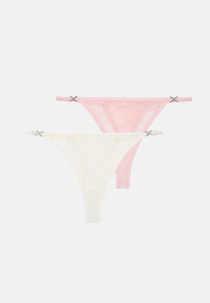 Deux strings en dentelle rose et blanc, chacun avec de petits nœuds décoratifs sur les côtés élastiques, présentés sur un fond blanc.