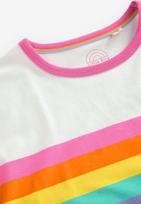 Fehér pamut póló kerek nyakkivágással, vízszintes csíkokkal rózsaszín, narancs, sárga, zöld és kék színekben. Logó a nyakkivágás belső oldalán nyomtatva.