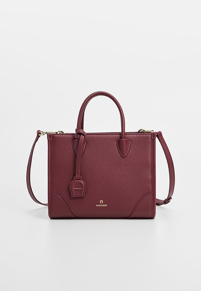 Burgunderfarbene Lederhandtasche mit strukturiertem Design, zwei oberen Griffen, abnehmbarem Schulterriemen, goldfarbener Hardware und texturierter Oberfläche.