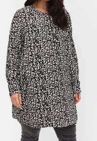 Tunique à motifs noirs et blancs, avec des manches longues, un col arrondi et une coupe ample, arborant un design abstrait éclaboussé.