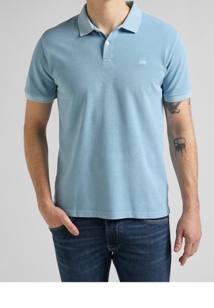 Lyseblå polo-skjorte i et struktureret stof med klassisk krave, tre-knaps placket og lille logo på brystet.