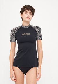 Short-sleeve black rash guard with intricate white patterns on sleeves. Rip Curl logo in gold on the front. Made from smooth, stretchy material.
