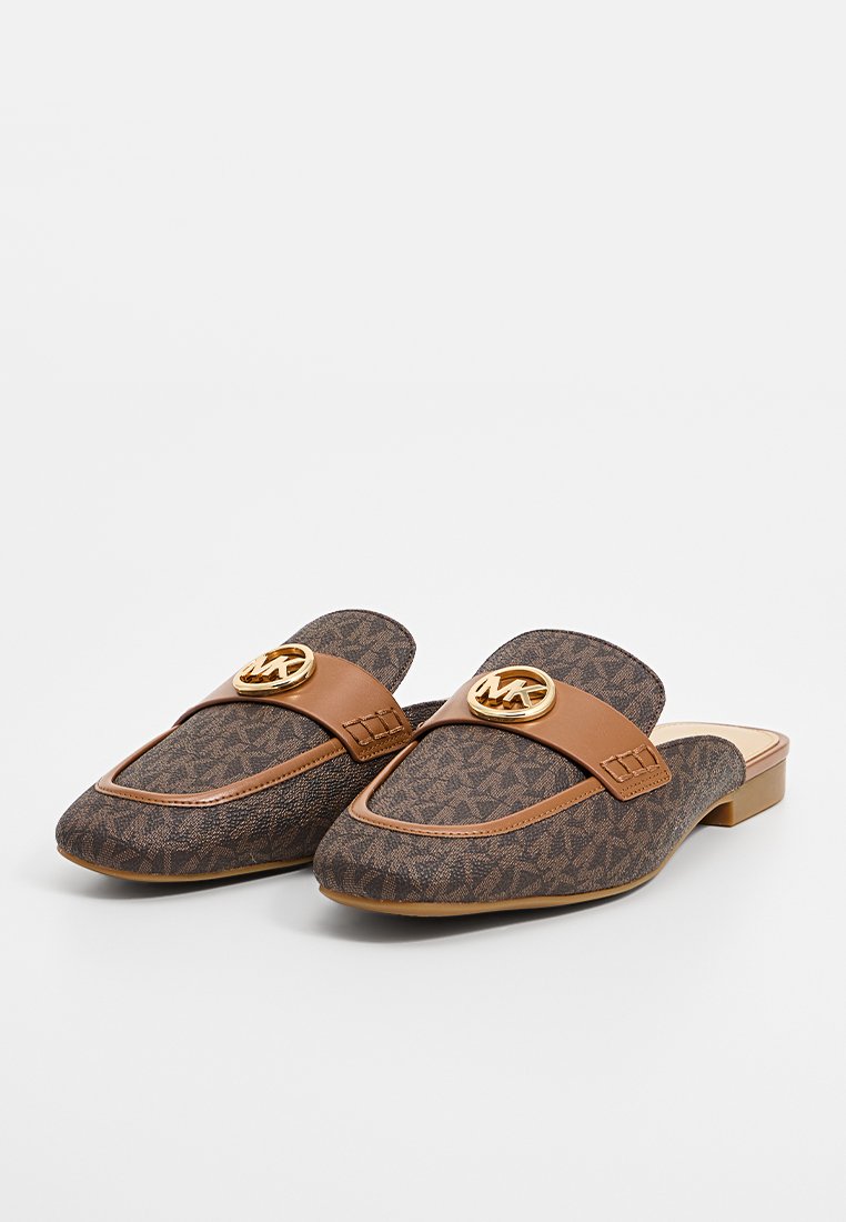 Bruine stoffen muiltjes met een gestructureerd patroon, voorzien van een tan neplederen band en een gouden embleemaccent aan de voorkant. Ontwerp met een lage blokhak.