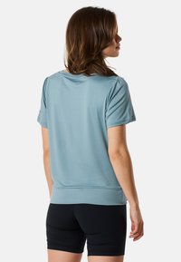 Kortärmad, ljusblå sportskjorta gjord av mjukt tyg, med en avslappnad passform och slät textur. Matchad med svarta shorts.