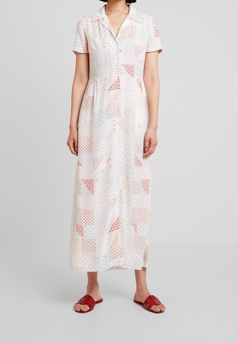 Maxi dress made of lightweight fabric featuring a white base with red and blue geometric patterns, collared neckline, and short sleeves.