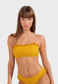 Yellow bikini set featuring a strapless top with ruffle trim and matching high-waisted bottoms with similar ruffled accents. Smooth texture.
