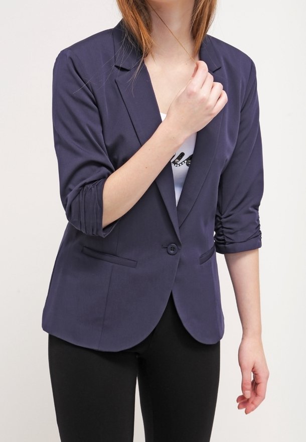 Granatowa marynarka z podwiniętymi rękawami, z pojedynczym zapięciem na guzik i dwoma bocznymi kieszeniami; wykonana z gładkiego materiału o dopasowanym kroju.