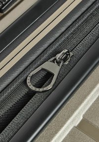 Erweiterbarer Koffer mit Reißverschlussdetail, silberner Metall-Ziehlasche, schwarzem strukturiertem Stoff und kontrastierenden glatten beigen Akzenten.