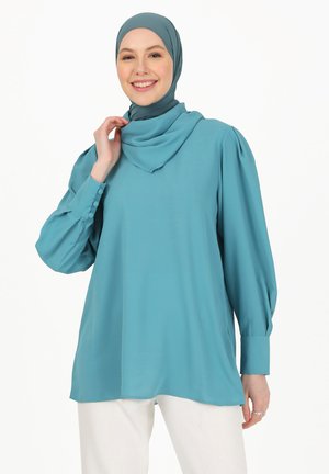 Turquoise blouse with long, puffed sleeves and buttoned cuffs; smooth, lightweight fabric; paired with a matching hijab.