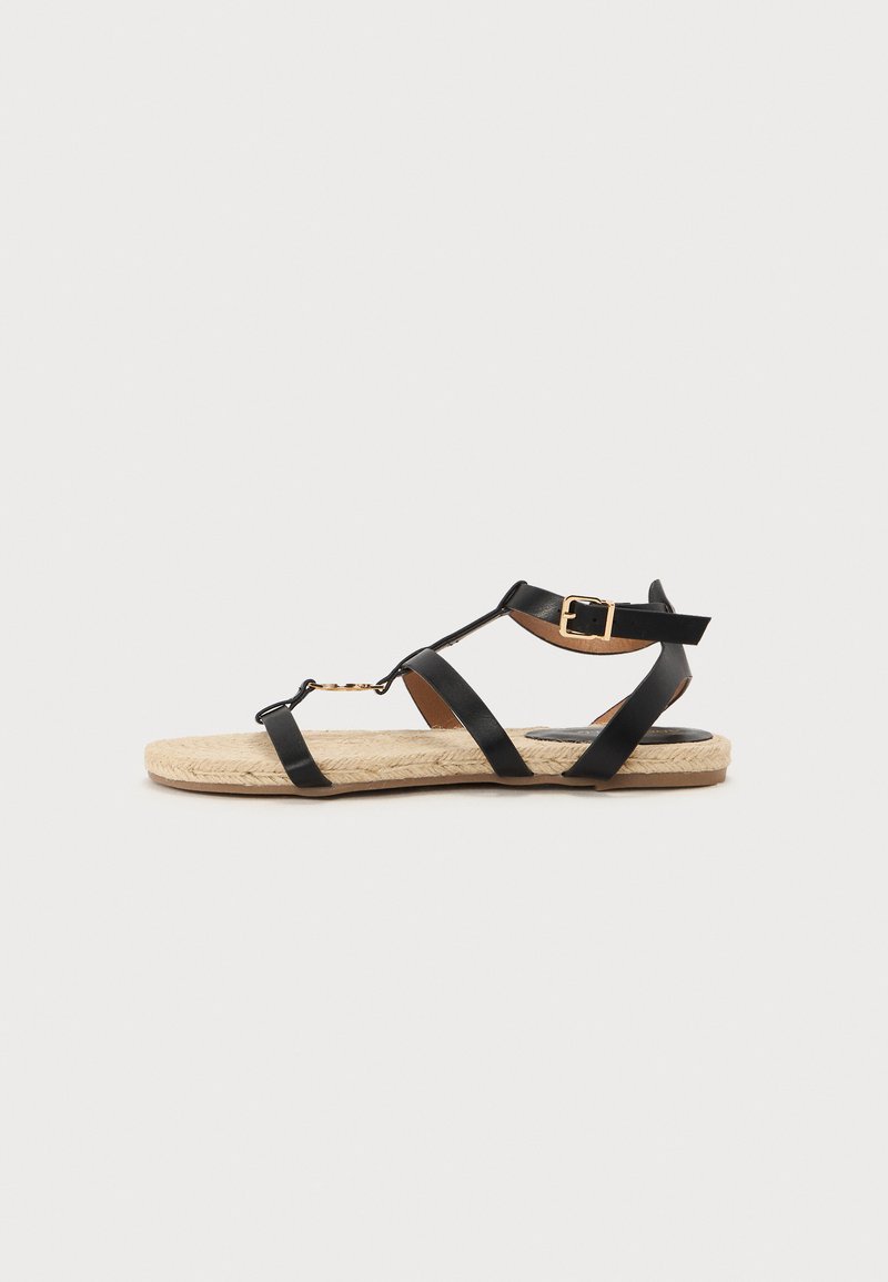 Mustat nahkaiset remmikengät, joissa on espadrille-pohja, säädettävä nilkkaremmi ja kultaisista komponenteista koostuvia korostuksia.